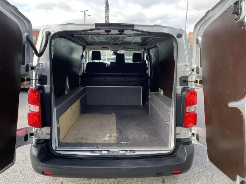 Vue arrière du Peugeot Expert Fourgon gris métal 2018, portes ouvertes montrant l'espace de chargement vide et l'intérieur utilitaire.
