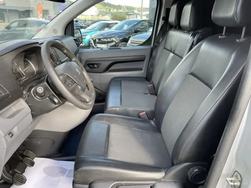 Vue intérieure côté conducteur du Peugeot Expert Fourgon 2018, sièges en cuir noir et tableau de bord gris clair.