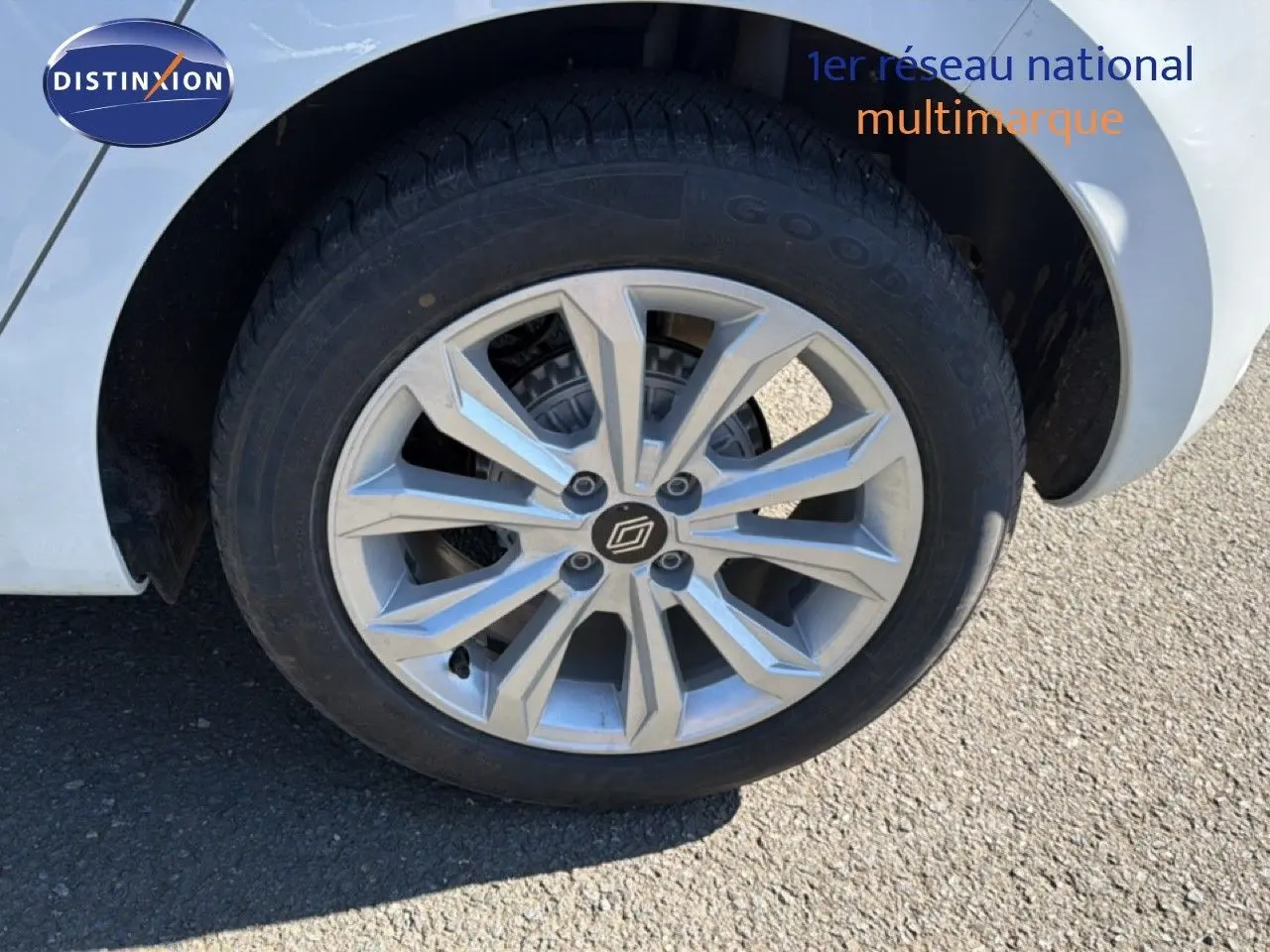 Gros plan sur la roue avant droite d'une Renault Clio blanche avec jante alliage à motif géométrique.