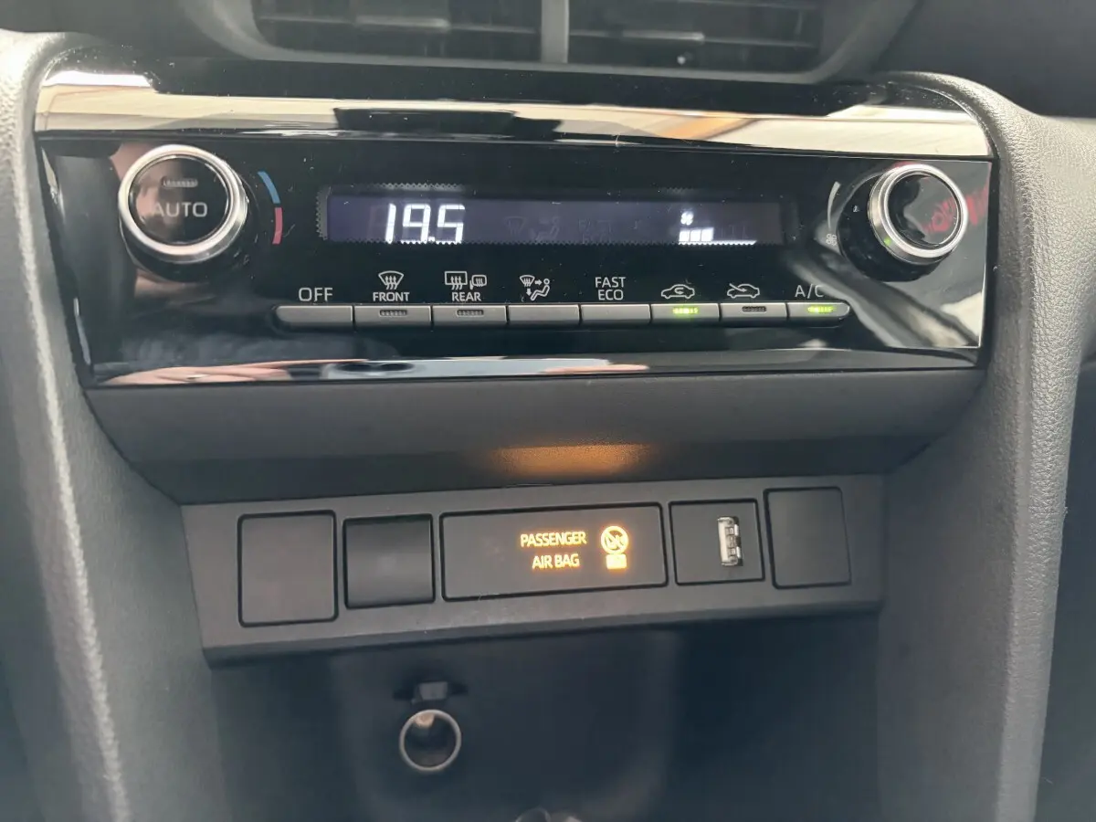 Gros plan sur la console centrale de la Toyota Yaris Cross 2024 gris clair, affichant la climatisation digitale à 19,5°C.