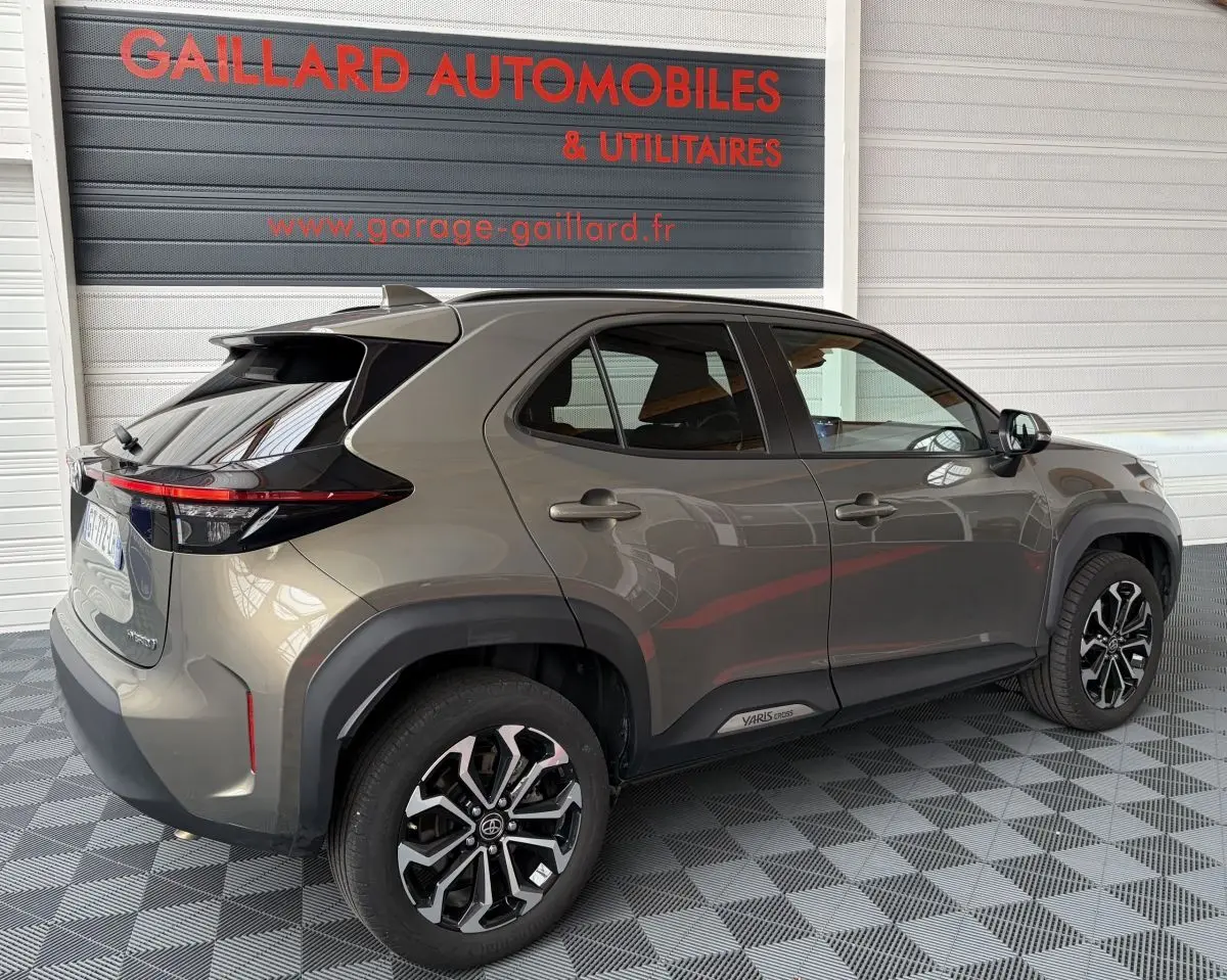 Vue 3/4 arrière droite d'une Toyota Yaris Cross gris clair 2024 avec jantes alliage et feux arrière LED.