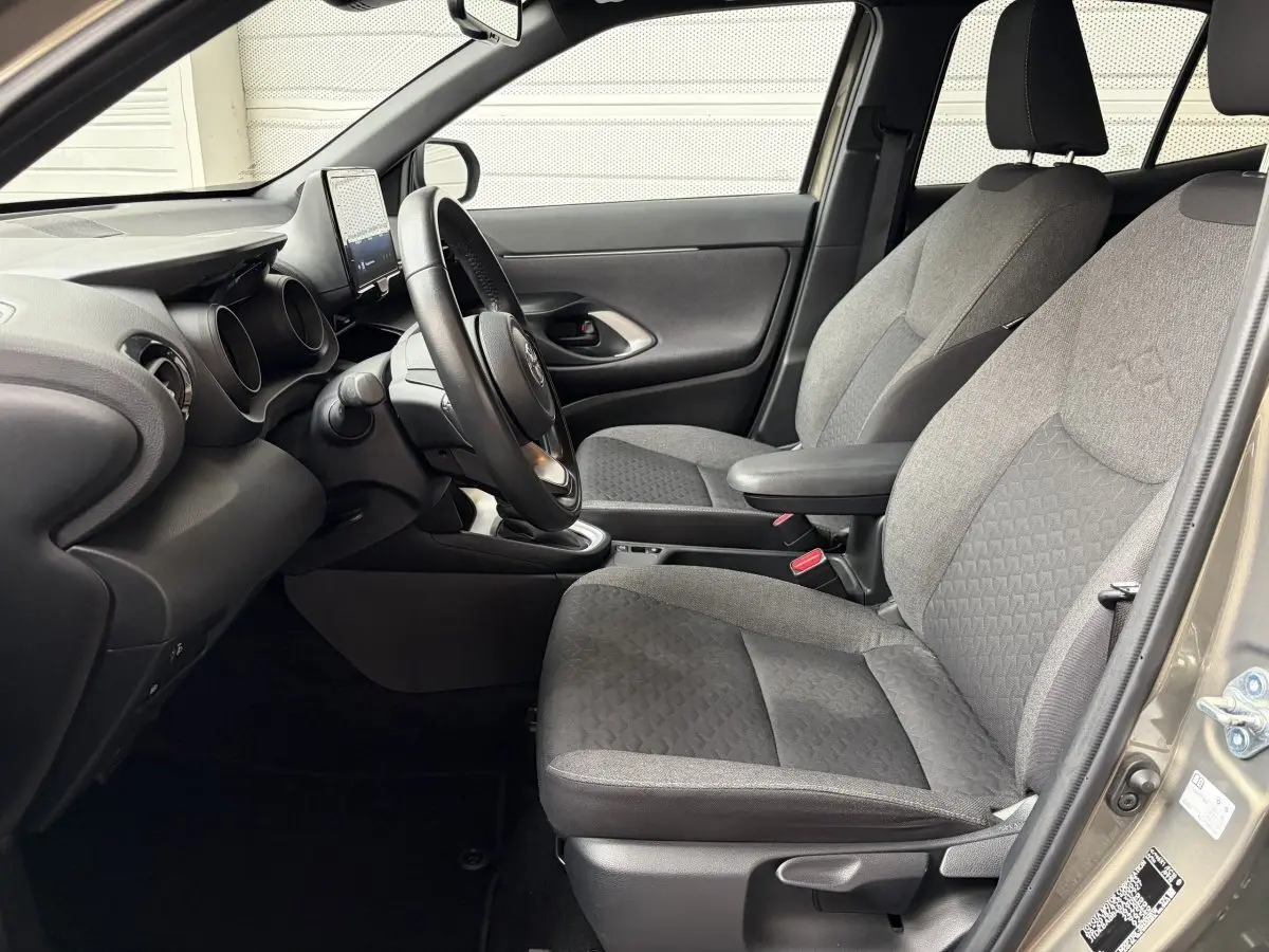 Vue intérieure côté conducteur de la Toyota Yaris Cross 2024 gris clair, volant cuir multifonctions et sièges tissu gris.