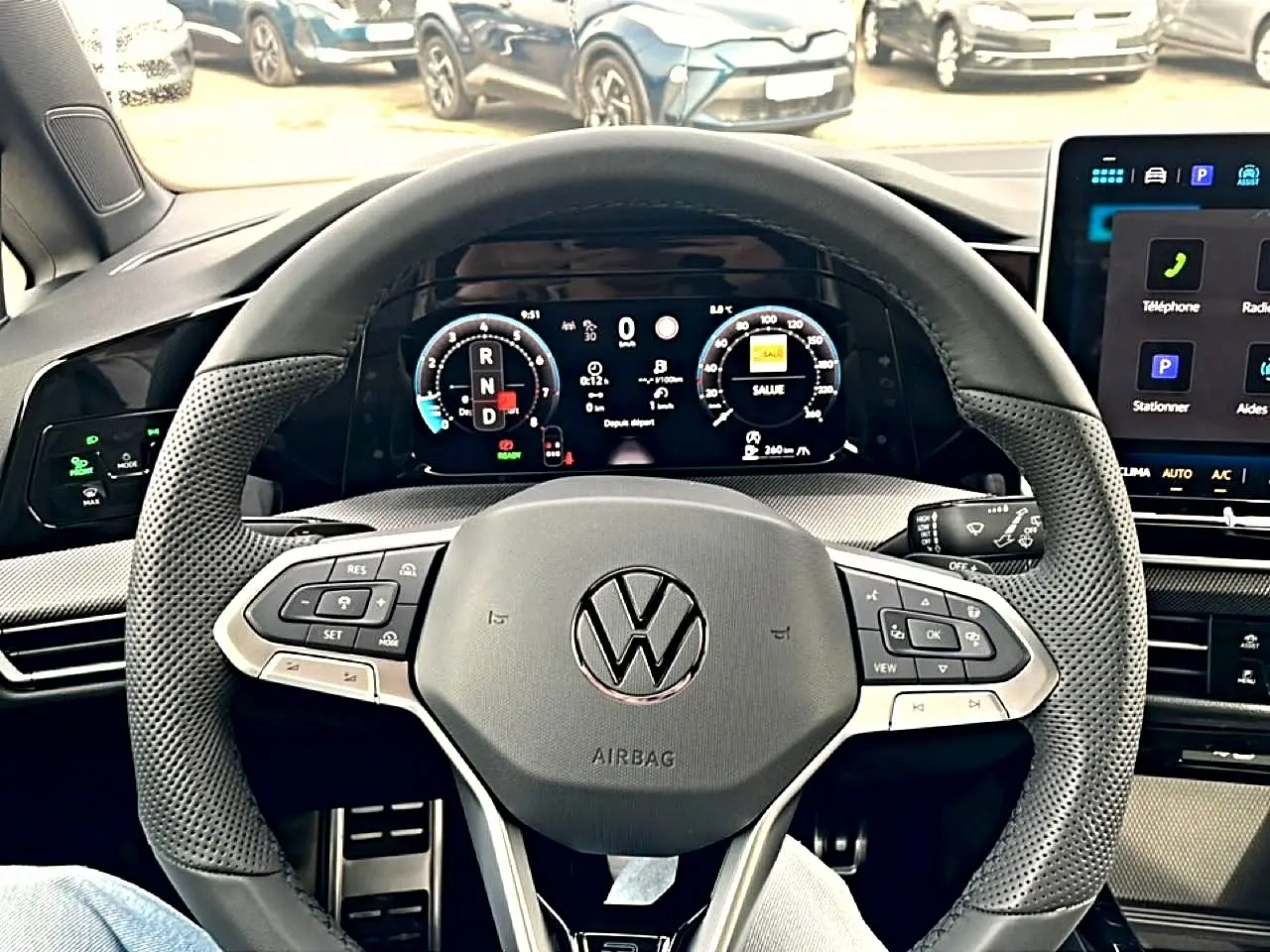 Vue intérieure centrée sur le volant cuir perforé et tableau de bord numérique de la Volkswagen Golf noire 2026.