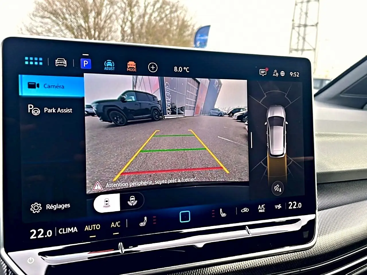 Écran tactile intérieur affichant la caméra de recul et l'aide au stationnement d'une Volkswagen Golf noire.