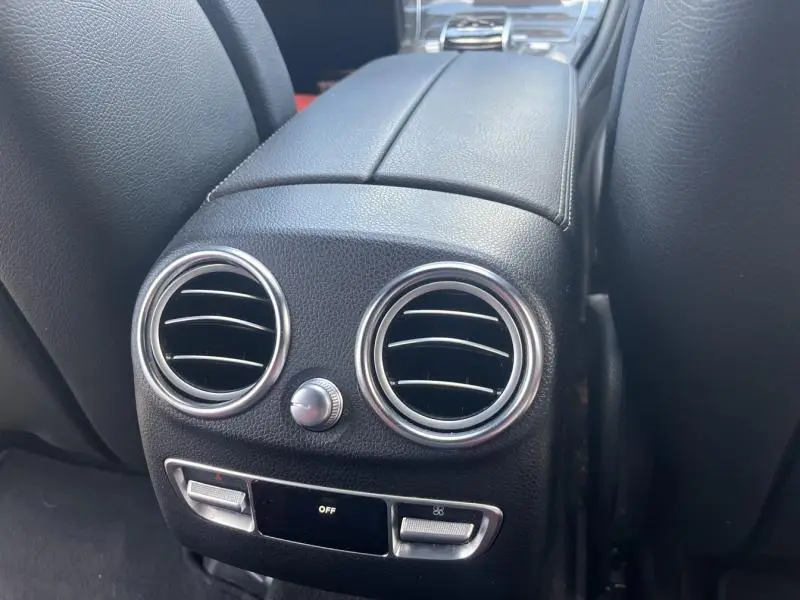 Gros plan sur la console arrière noire avec aérateurs ronds et commandes climatisation du Mercedes GLC Coupé blanc diamant