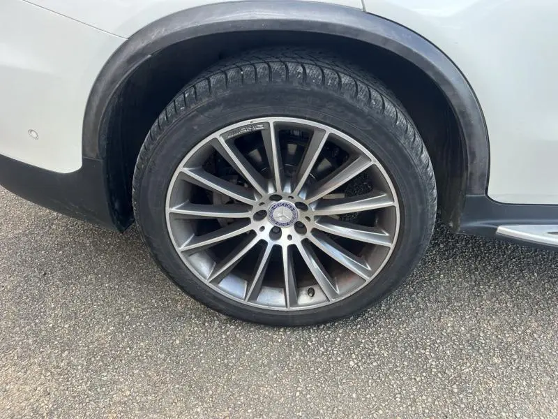 Gros plan sur la roue arrière droite du Mercedes GLC Coupé blanc diamant avec jante AMG 20 multibranches bicolore