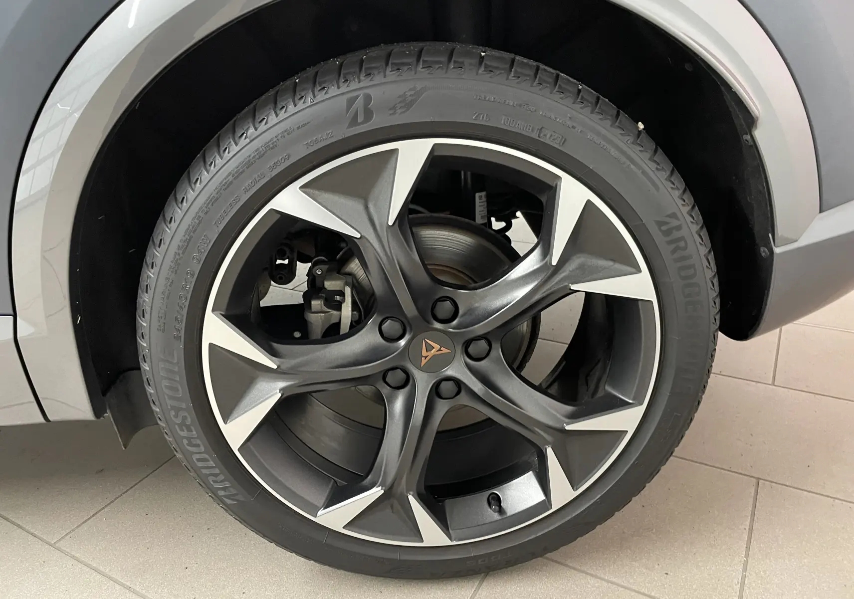 Gros plan sur la jante avant droite du CUPRA Formentor gris magnétique mat, avec logo CUPRA au centre et pneus Bridgestone.