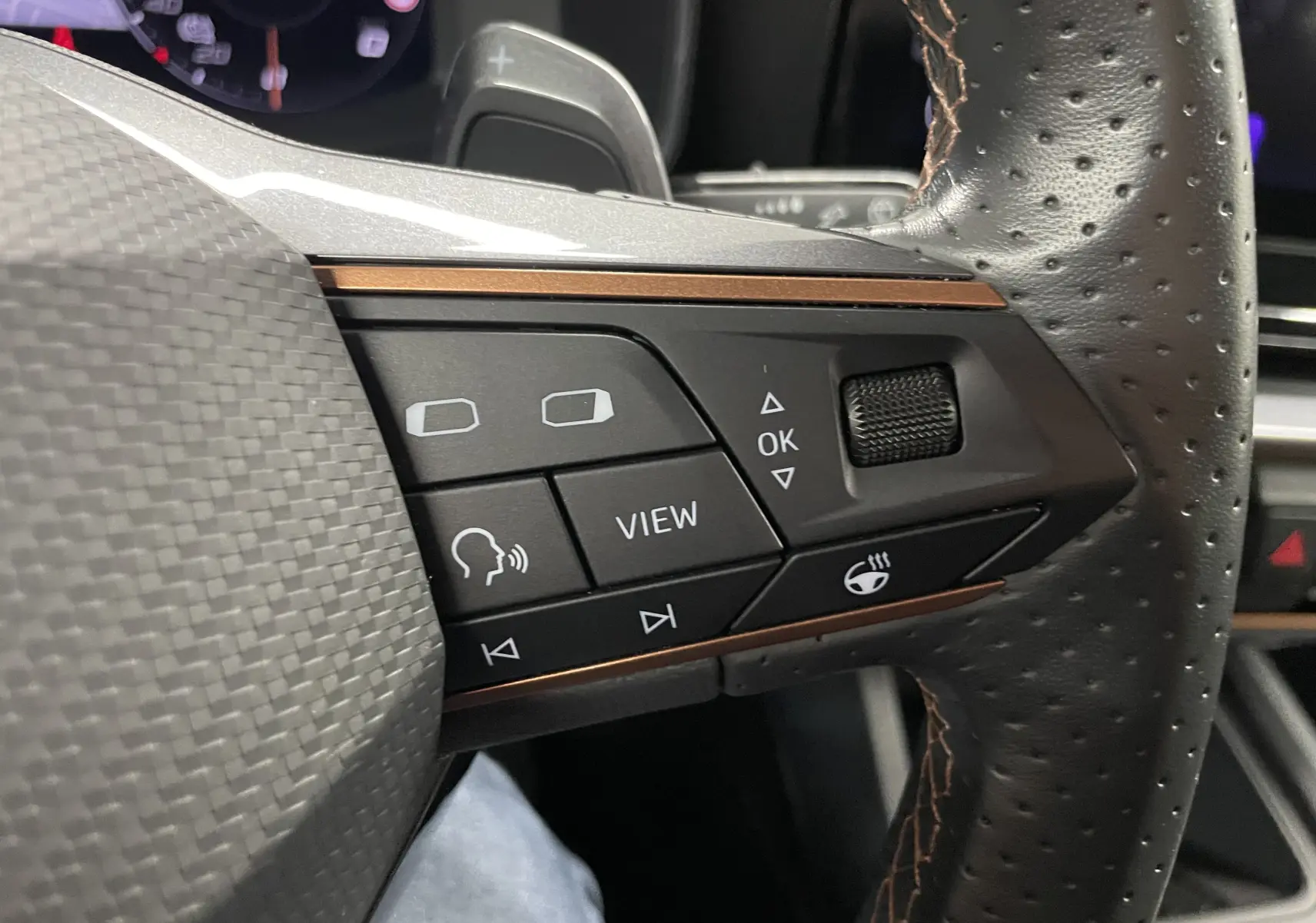 Gros plan sur les commandes du volant cuir perforé du CUPRA Formentor 1.5 TSI gris magnétique mat, avec touches multifonctions et molette.