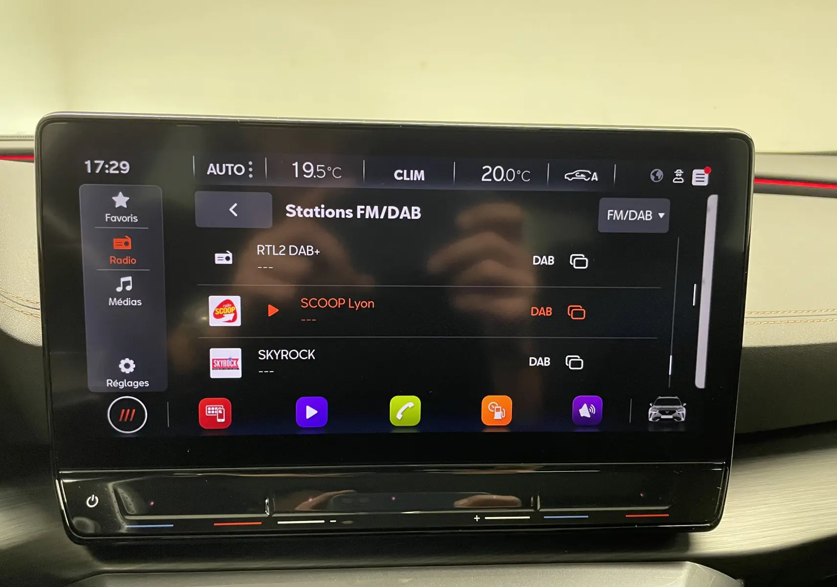 Écran tactile central du tableau de bord du CUPRA Formentor affichant les stations radio FM/DAB avec ambiance intérieure moderne.