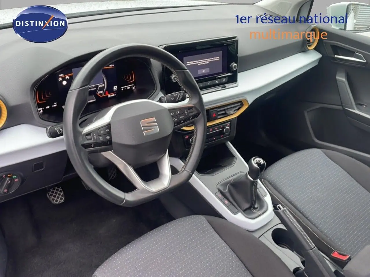Vue intérieure du poste de conduite du SEAT Arona 2025, volant cuir, tableau de bord moderne et levier de vitesses manuel.