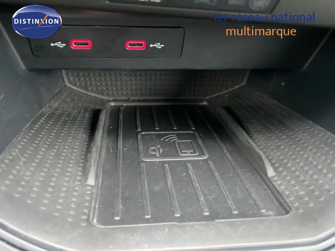 Vue rapprochée de la console centrale du SEAT Arona 2025, avec chargeur sans fil et ports USB rouges visibles.