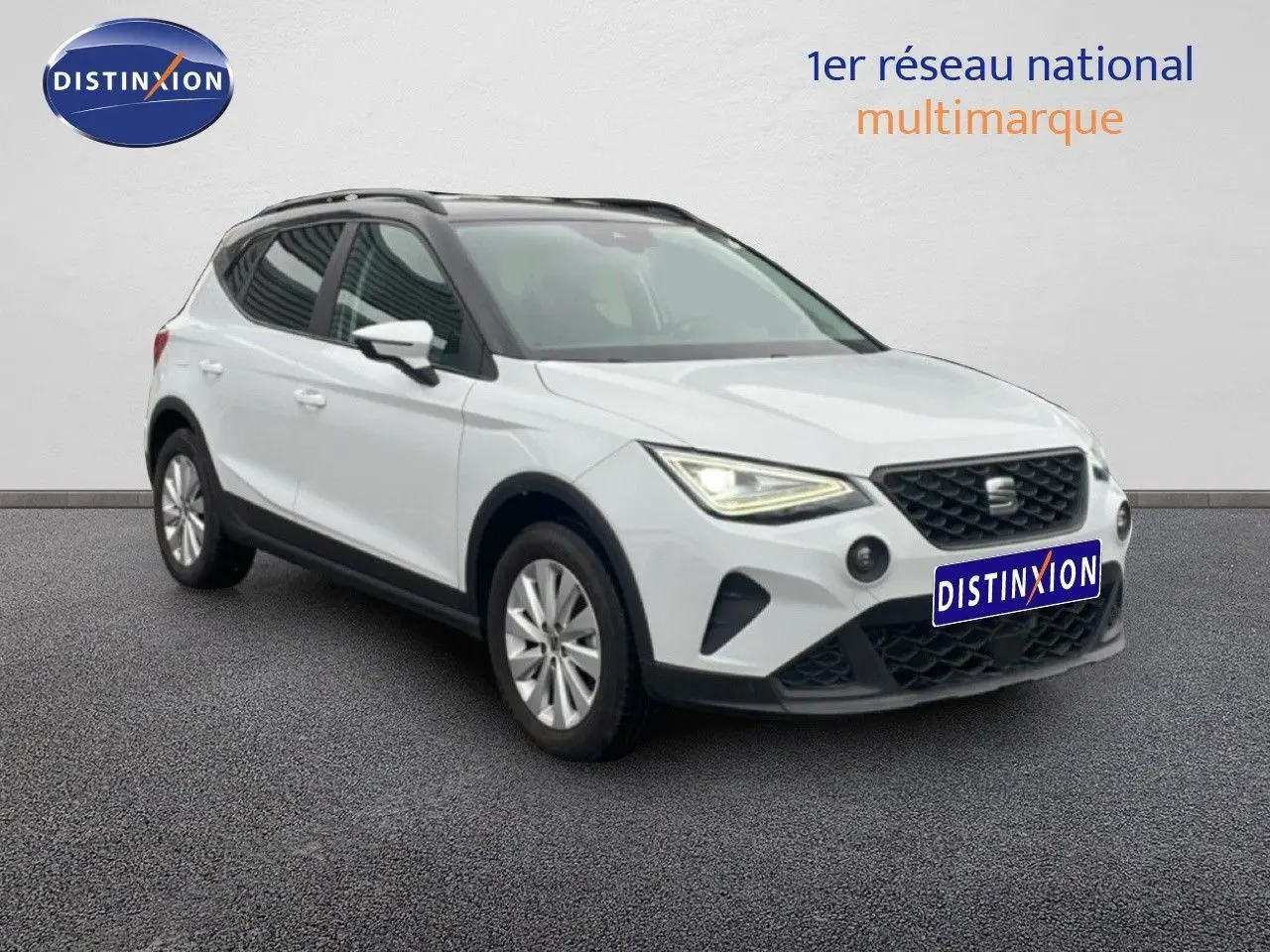 SEAT Arona blanc alpin métal avec toit noir, vue 3/4 avant droit, phares allumés sur fond neutre.