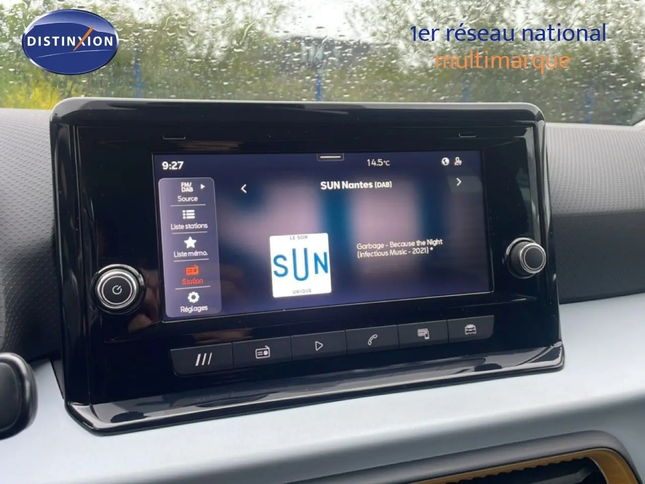 Écran tactile central du tableau de bord d'une SEAT Arona 2025, affichant une radio numérique sous pluie.