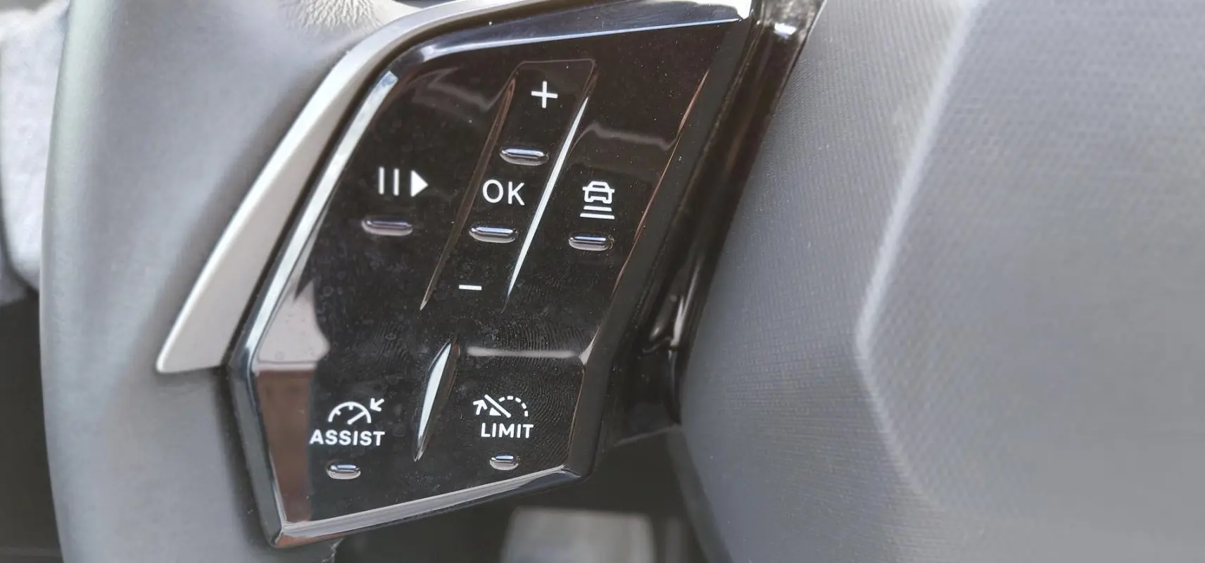 Gros plan sur les commandes au volant noir du Peugeot 3008 Hybrid 136 e-DCS6 Allure, avec boutons de régulateur et limiteur.