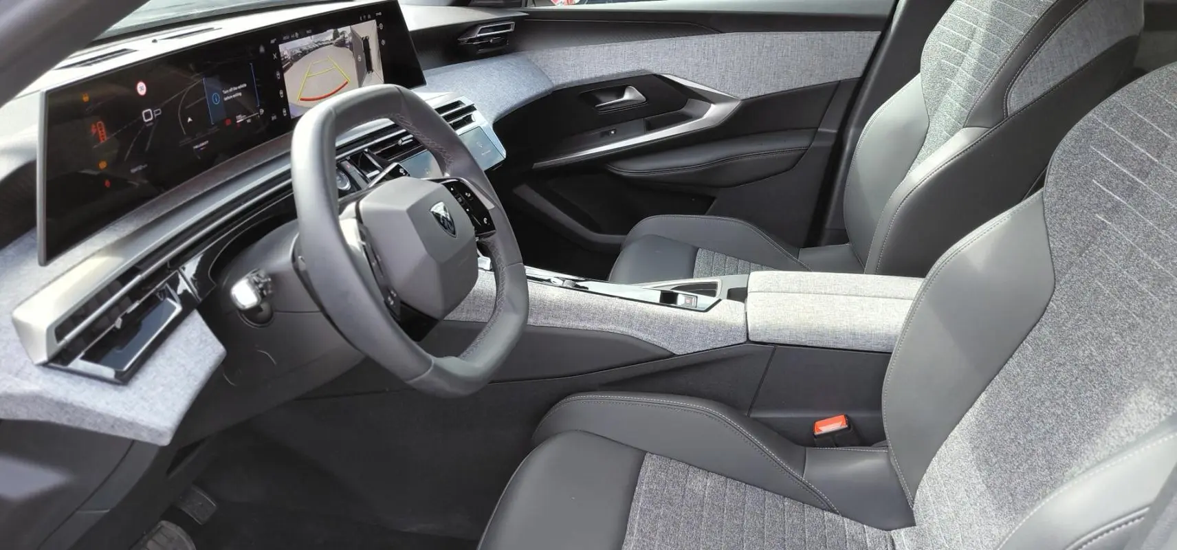 Vue intérieure côté conducteur du Peugeot 3008 Hybrid 136 e-DCS6 Allure 2025, avec cockpit numérique et sellerie grise tissu et cuir.