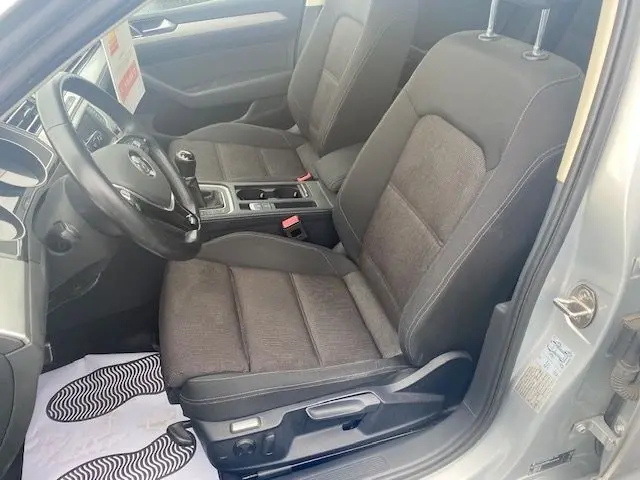 Intérieur côté conducteur d'une Volkswagen Passat reflet d'argent 2015, sièges tissu gris et volant noir visible.