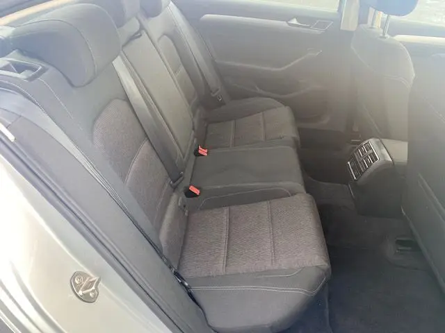 Vue intérieure arrière côté gauche de la Volkswagen Passat Confortline Business 2015, sièges tissu gris et porte argentée ouverte.