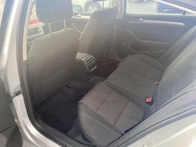 Vue intérieure arrière côté gauche d'une Volkswagen Passat 2015 reflet d'argent, sièges tissu gris et console centrale avec aérateurs.