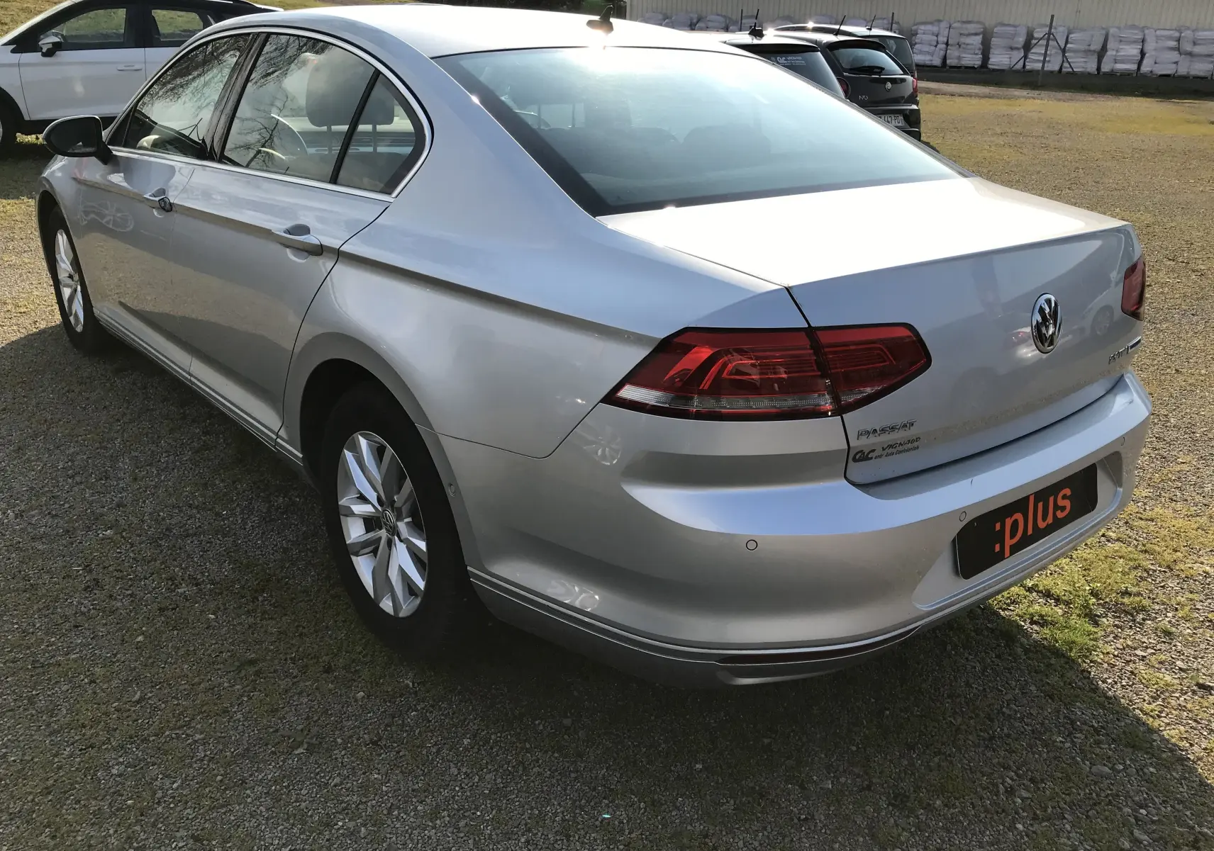 Vue 3/4 arrière droite d'une Volkswagen Passat Confortline Business 2015 en reflet d'argent avec feux arrière LED et jantes alliage.