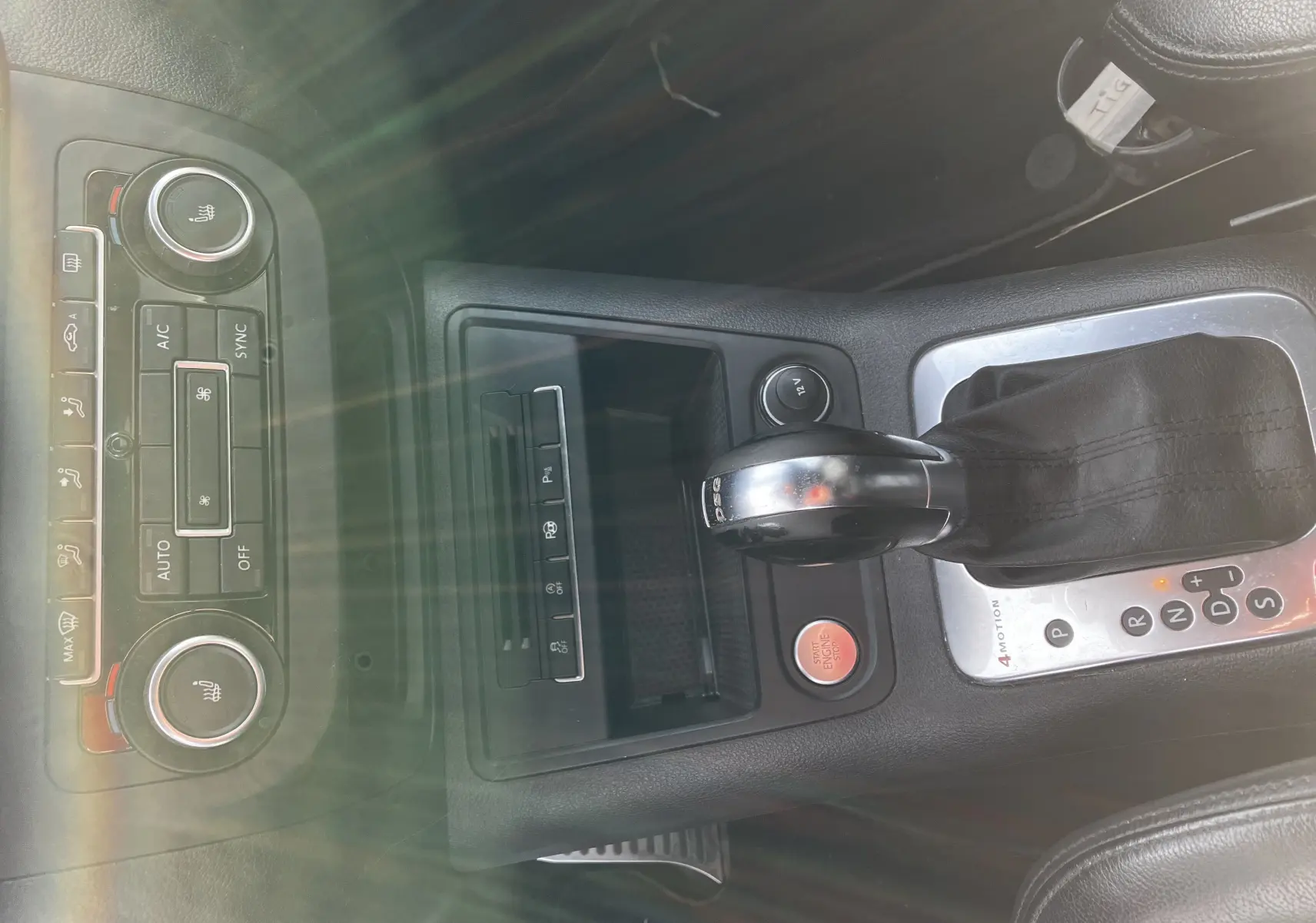 Vue rapprochée de la console centrale noire du Volkswagen Tiguan blanc 2013, avec levier de vitesse DSG et commandes climatisation.