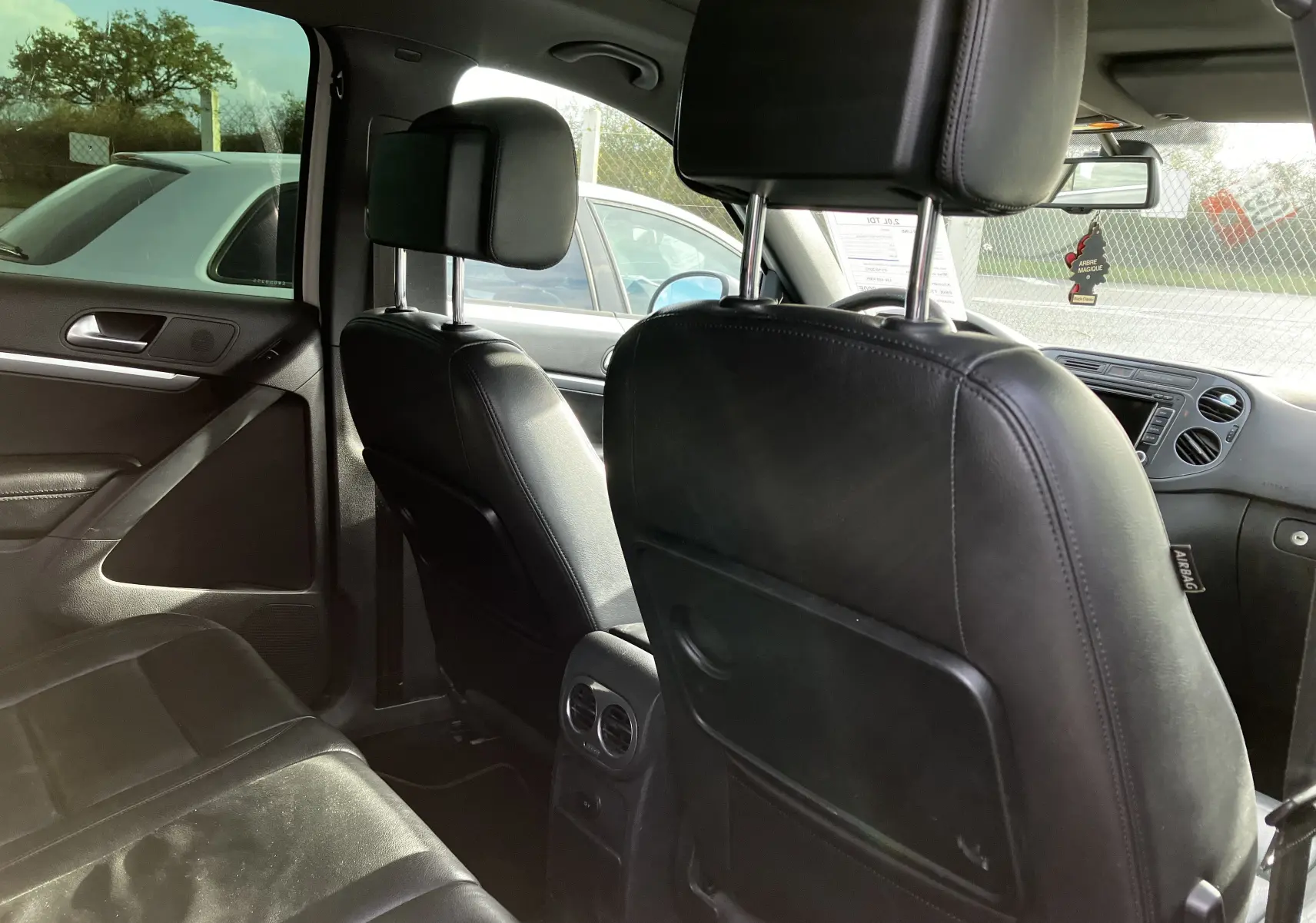 Vue intérieure arrière du Volkswagen Tiguan 2013, sièges en cuir noir et ventilation centrale entre les sièges avant.