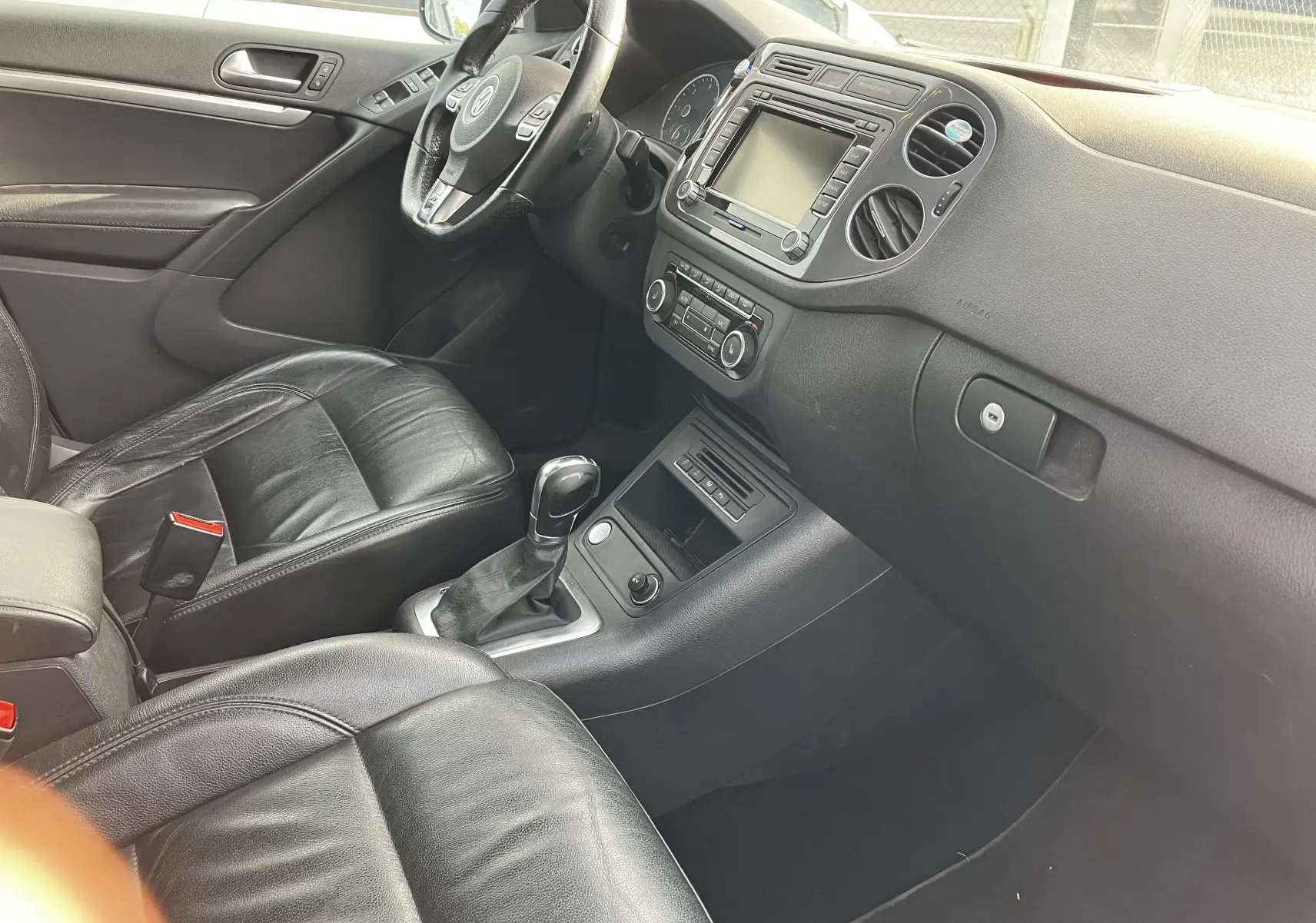 Intérieur noir cuir du Volkswagen Tiguan 2013, vue côté conducteur sur le tableau de bord et la console centrale.