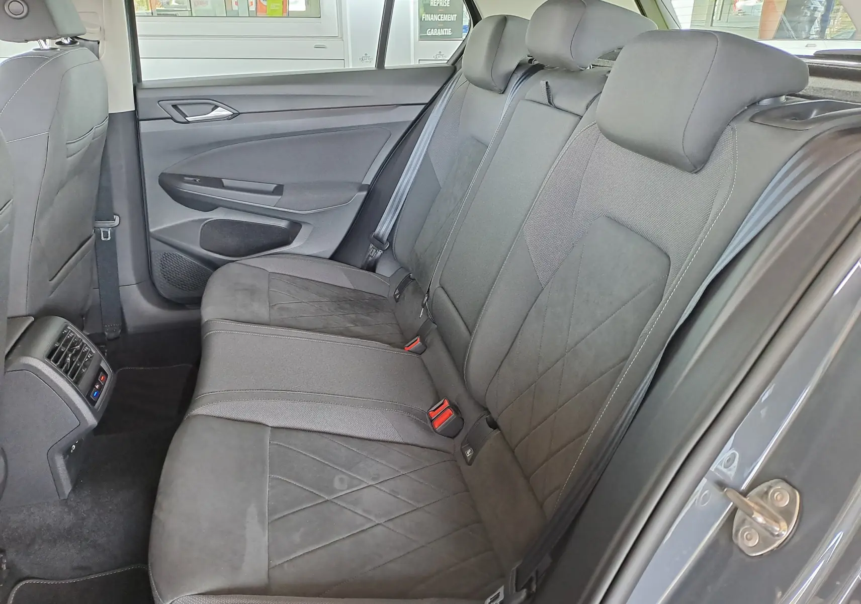 Vue intérieure côté droit des sièges arrière gris foncé de la Volkswagen Golf VIII 1.4 e-Hybrid 2021, avec ceintures et aérateurs centraux.