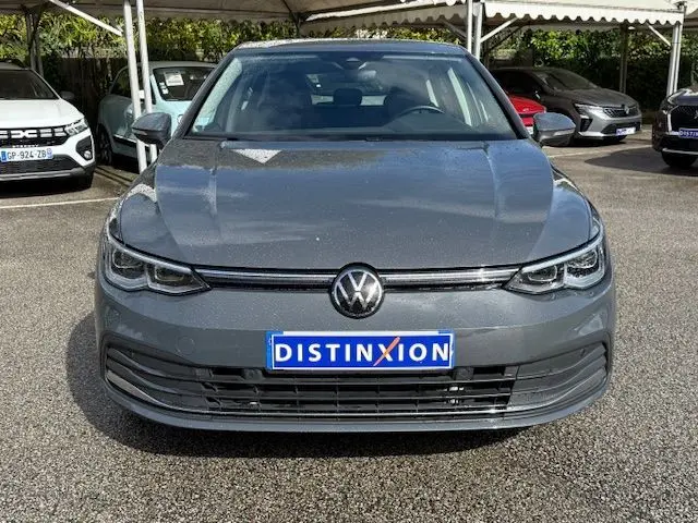 Vue frontale d'une Volkswagen Golf VIII 1.4 e-Hybrid gris dauphin avec calandre et logo VW bien visibles.