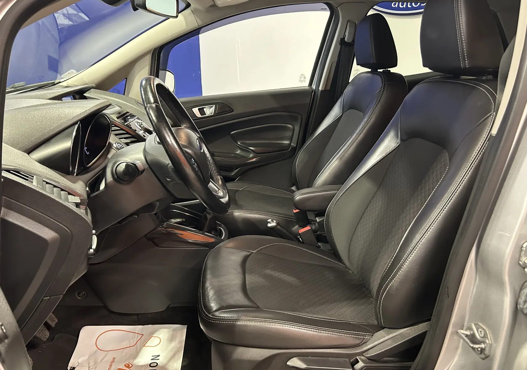 Vue intérieure côté gauche du Ford EcoSport gris 2018, sièges avant en cuir noir avec coutures blanches visibles.