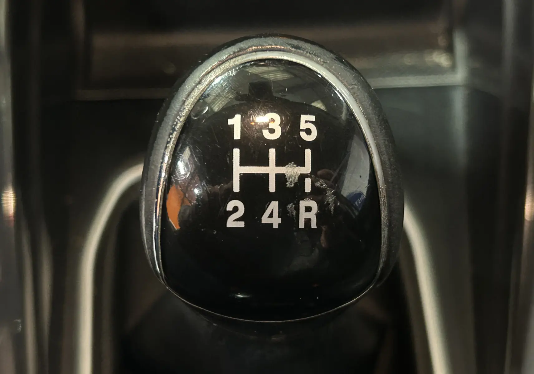 Gros plan sur le pommeau de la boîte manuelle noire du Ford EcoSport gris, affichant les vitesses 1 à 5 et la marche arrière.