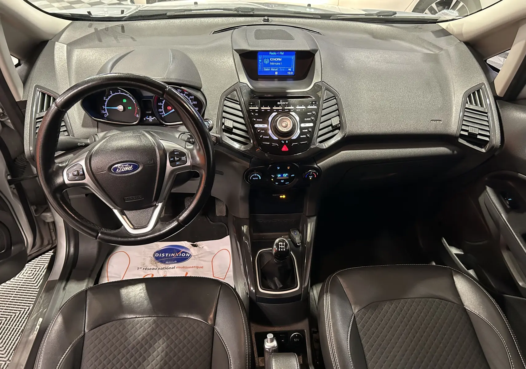 Vue intérieure avant du Ford EcoSport gris 2018, volant cuir multifonction, tableau de bord avec écran central et boîte manuelle.