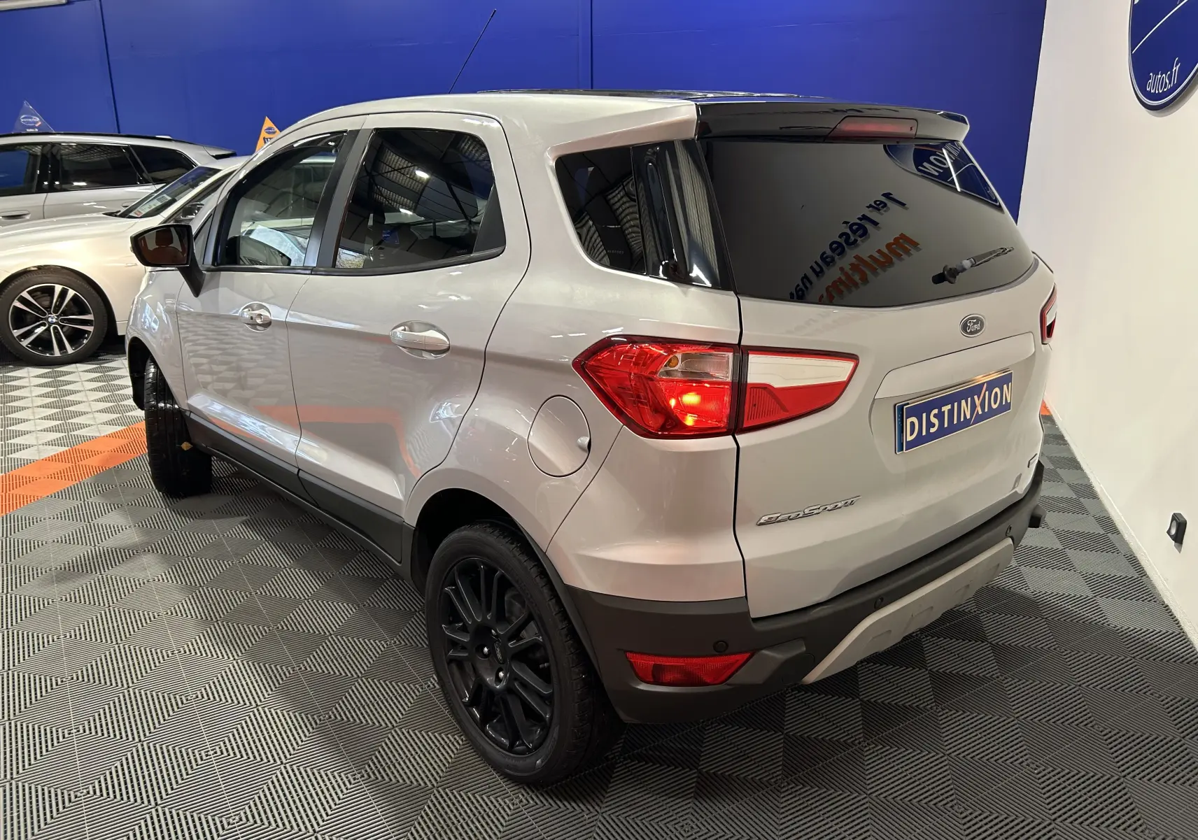 Vue 3/4 arrière droite d'un Ford EcoSport gris 2018 avec jantes noires et vitres teintées dans un showroom.