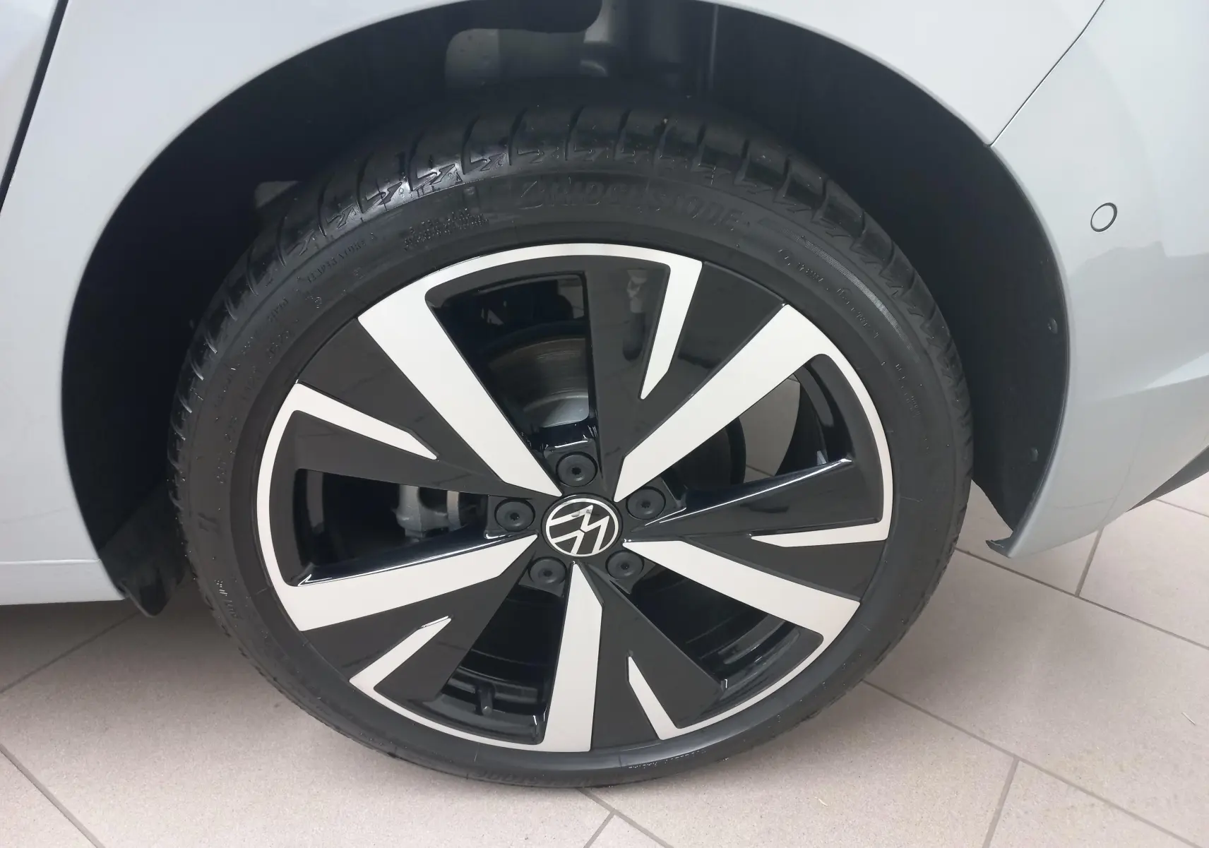 Gros plan sur la jante alliage 18'' Catania bicolore noir et argent du côté gauche d'une Volkswagen Golf 1.5 eHybrid 2025 argent Dolomite.