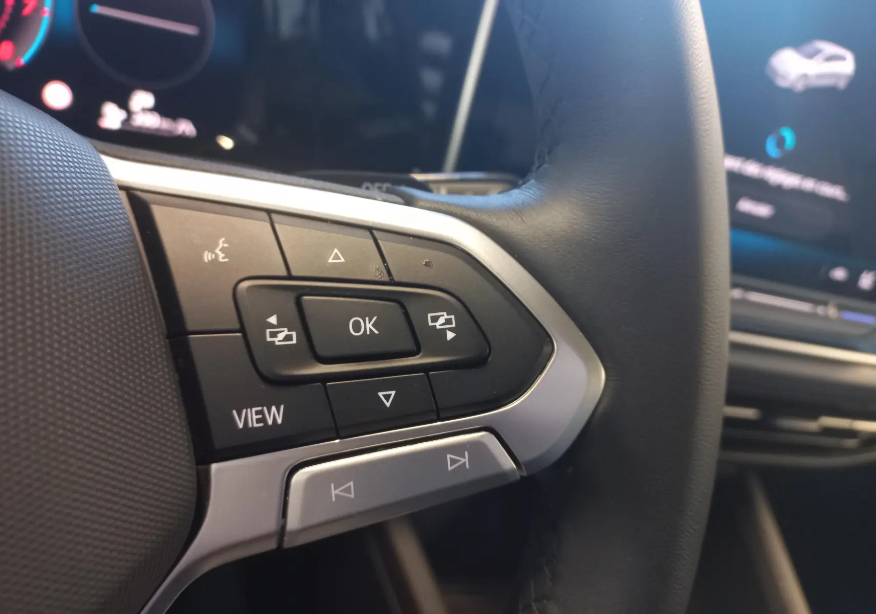 Gros plan sur les commandes au volant côté gauche d’une Volkswagen Golf 1.5 eHybrid 2025, intérieur noir.