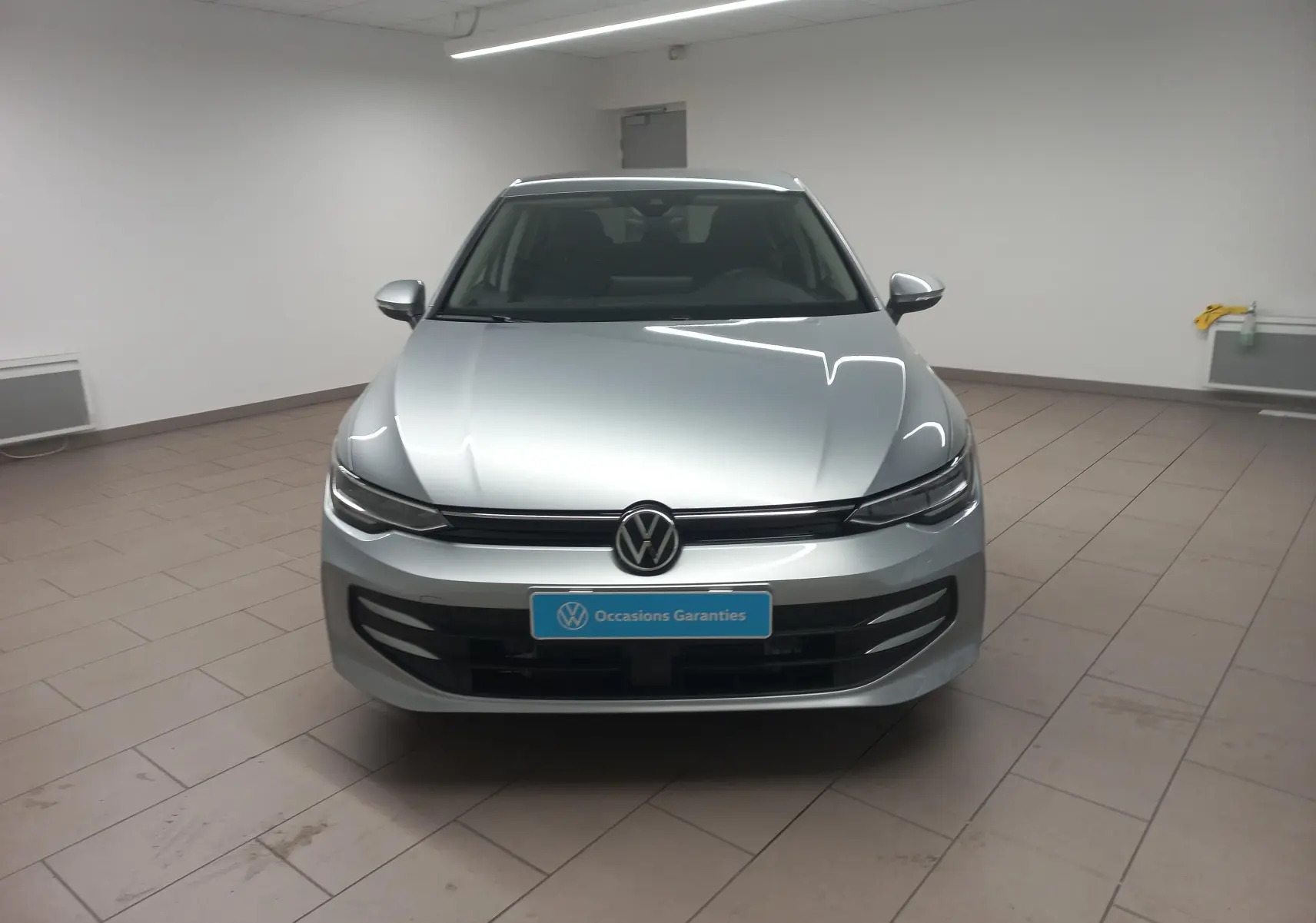 Vue de face d'une Volkswagen Golf 1.5 eHybrid 204 DSG6 en argent Dolomite avec calandre noire et logo VW central.