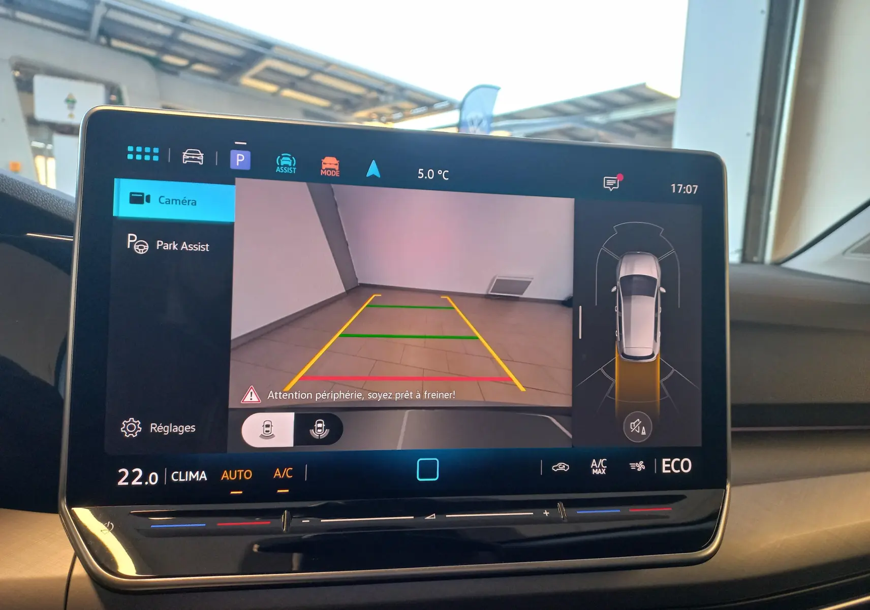 Écran tactile intérieur de la Volkswagen Golf 1.5 eHybrid 2025 affichant l'aide au stationnement avec vue caméra arrière et capteurs.