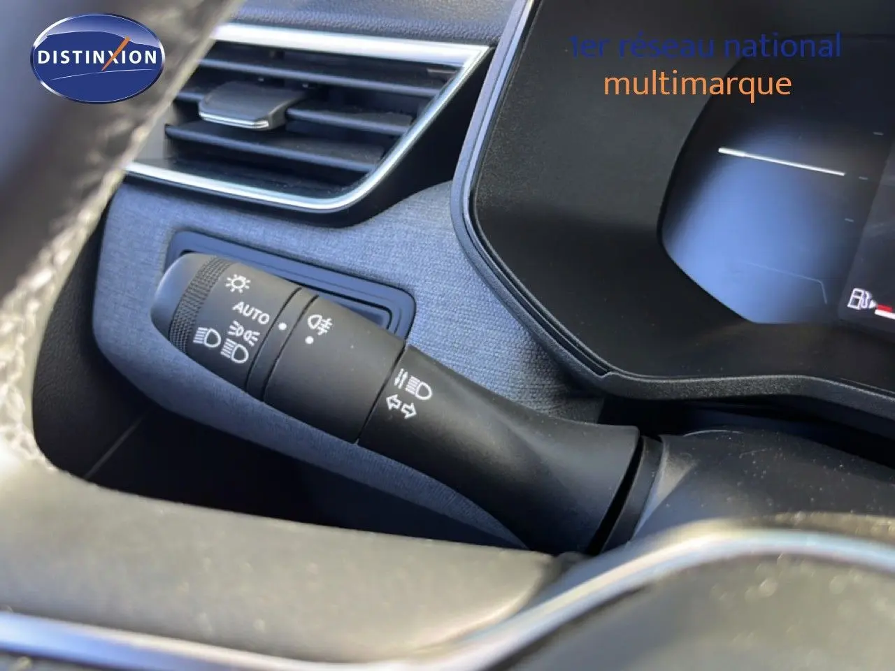 Gros plan sur la commande des phares et clignotants à gauche du volant dans l’habitacle d’une Renault Clio gris schiste métal.