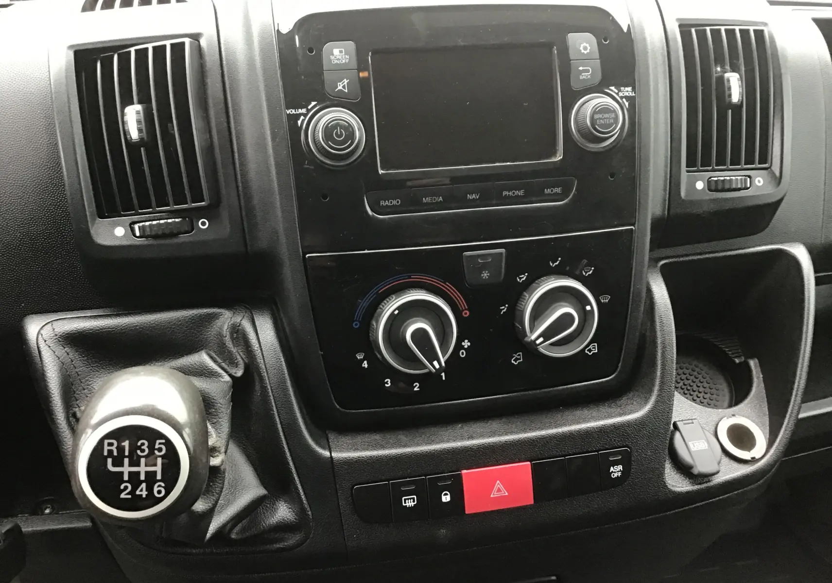 Vue rapprochée du tableau de bord noir du Fiat Ducato Fourgon 2021, avec levier de vitesses manuel et commandes centrales.