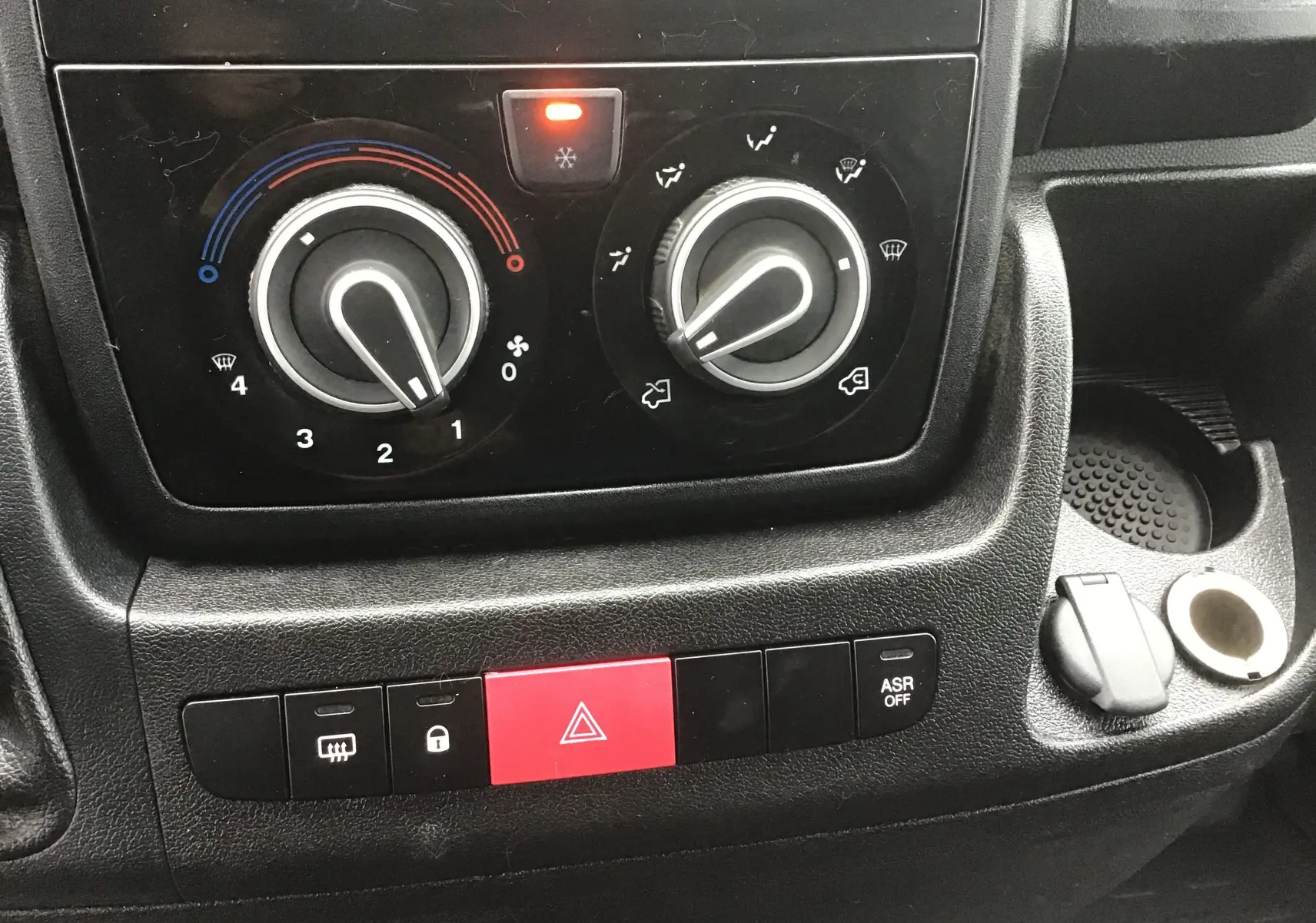 Gros plan sur la console centrale du Fiat Ducato Fourgon 2021, montrant les commandes de climatisation et les boutons de sécurité.