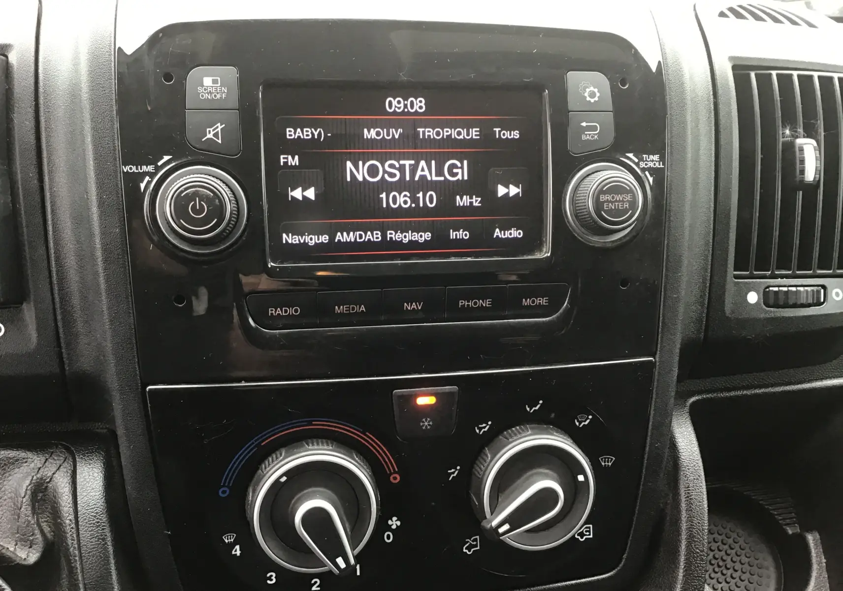 Vue rapprochée du tableau de bord noir du Fiat Ducato Fourgon 2021, avec écran radio affichant la station Nostalgie.