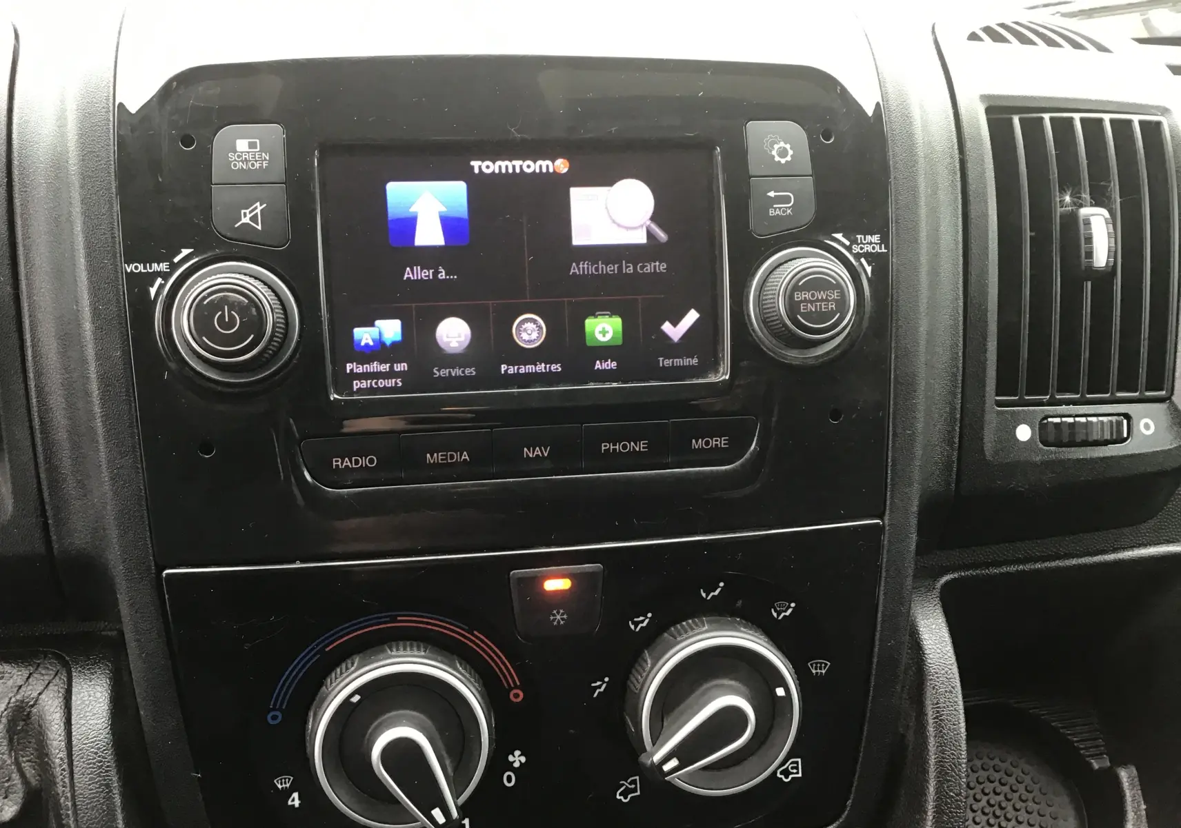 Vue rapprochée du tableau de bord noir du Fiat Ducato Fourgon 2021, avec écran tactile TomTom et commandes de climatisation.