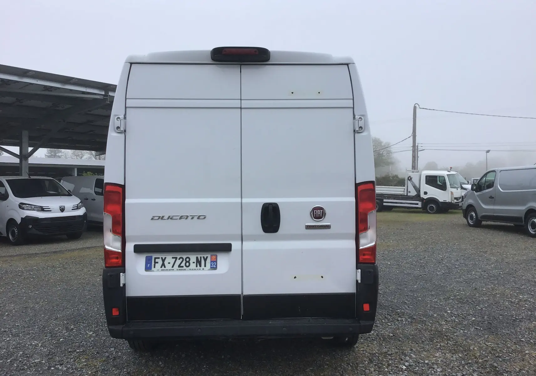 Vue arrière d'un FIAT Ducato Fourgon blanc, avec portes battantes fermées et plaques d'immatriculation françaises visibles.