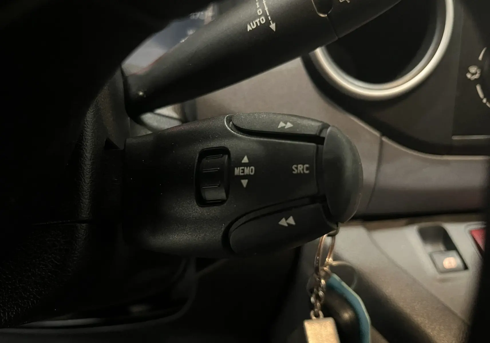 Gros plan sur la commande au volant du Peugeot Partner Tepee 2013, boutons SRC et MEMO visibles, intérieur gris foncé.