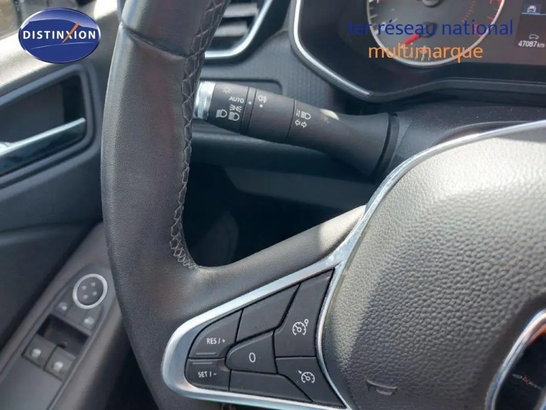 Vue rapprochée du volant de la Renault Clio blanc 2020, avec commandes de régulateur de vitesse et tableau de bord partiel.