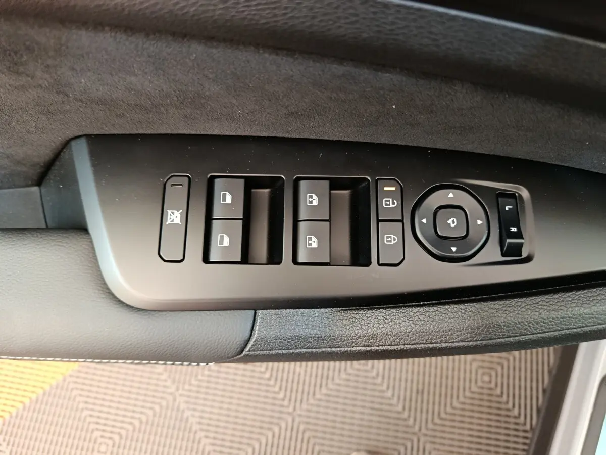 Gros plan sur les commandes de lève-vitres et rétroviseurs côté conducteur du KIA Sportage gris clair 2026.