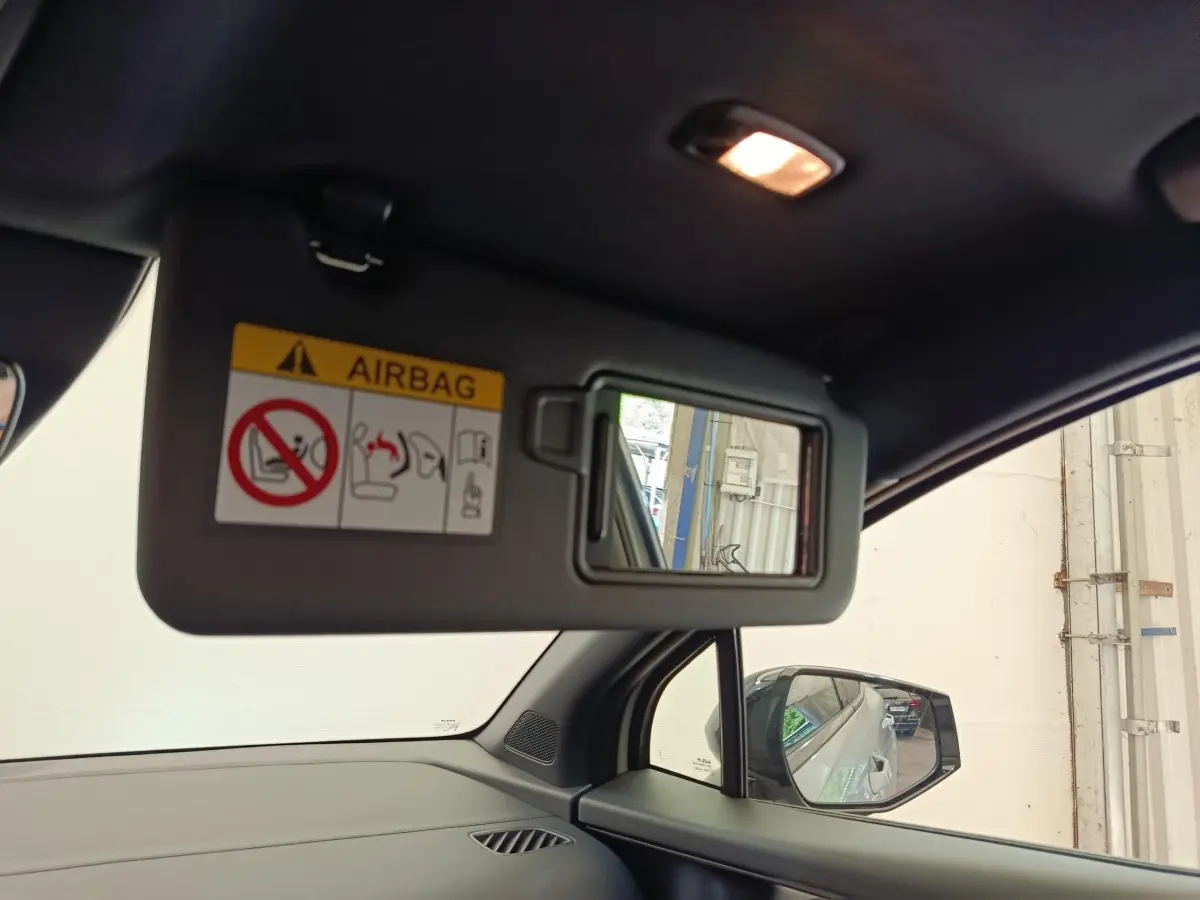 Détail de la visière côté conducteur avec miroir intégré et avertissement airbag, intérieur noir du Kia Sportage gris clair.