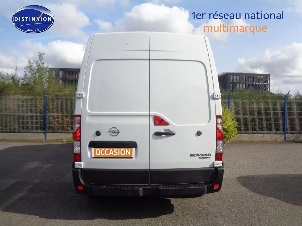 Vue arrière d’un fourgon Opel Movano blanc polaire avec portes battantes et logo distinctif sur parking.