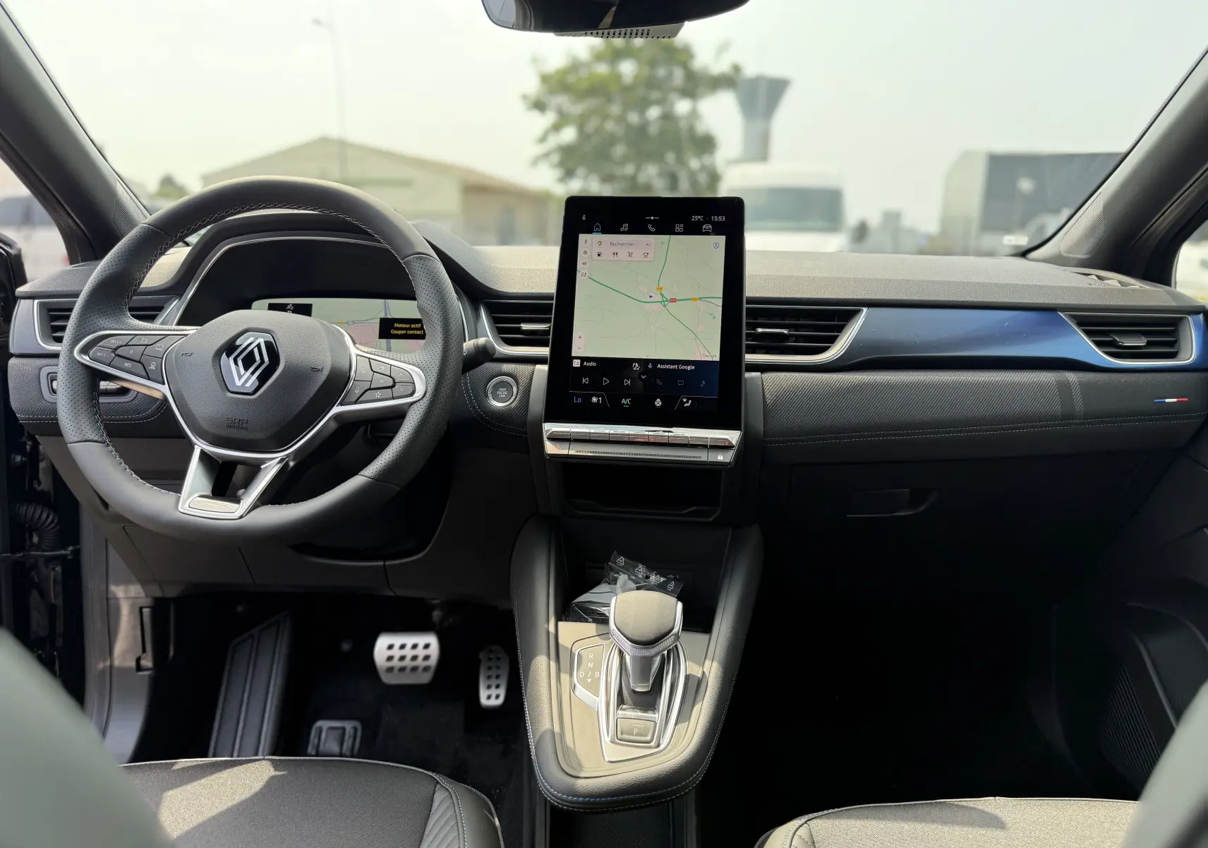 Intérieur du Renault Captur 2025 hybride, vue frontale du tableau de bord avec écran tactile vertical et volant noir.