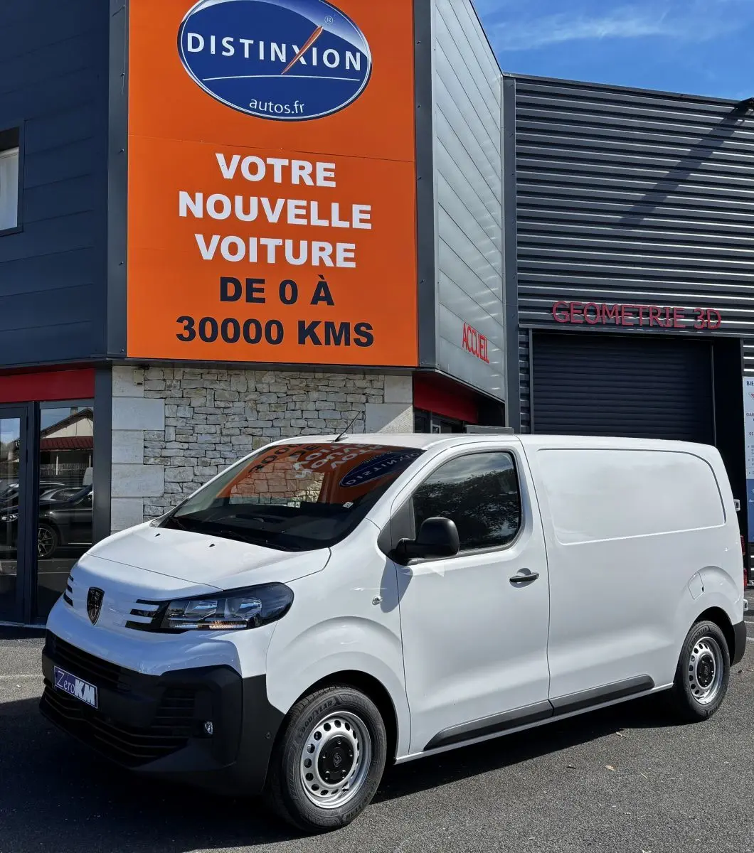 Peugeot Expert Fourgon blanc en 3/4 avant droit, stationné devant un bâtiment commercial avec panneau orange.