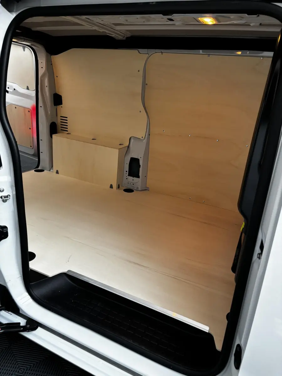 Intérieur du coffre du Peugeot Expert Fourgon blanc, vue latérale droite montrant l'aménagement bois clair et l'espace de chargement.